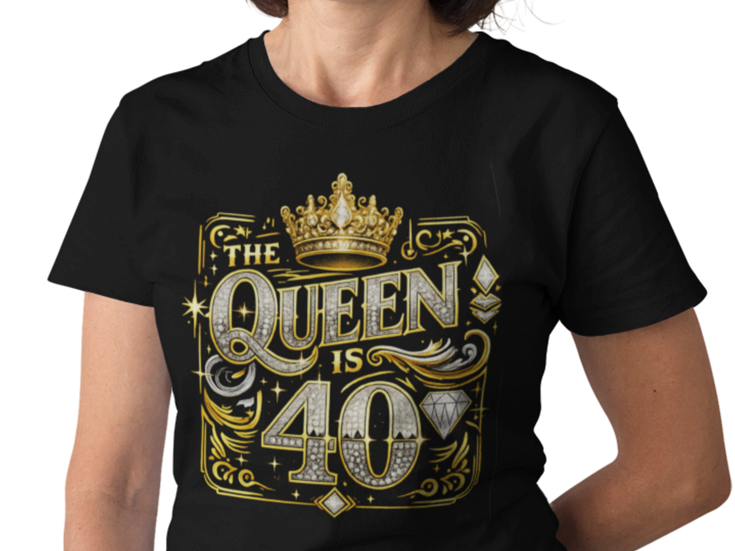 A woman wearing a black short-sleeve t-shirt with a large gold and silver graphic on the front that reads 'THE QUEEN IS 40' with a crown and diamond motifs, against a plain white background.
