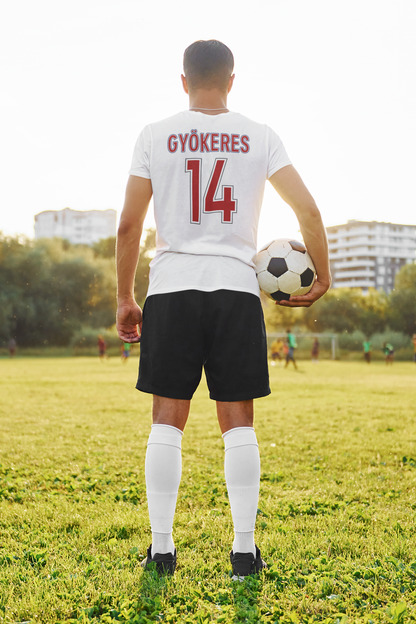 Soccer player holding a ball on a field with buildings in the background