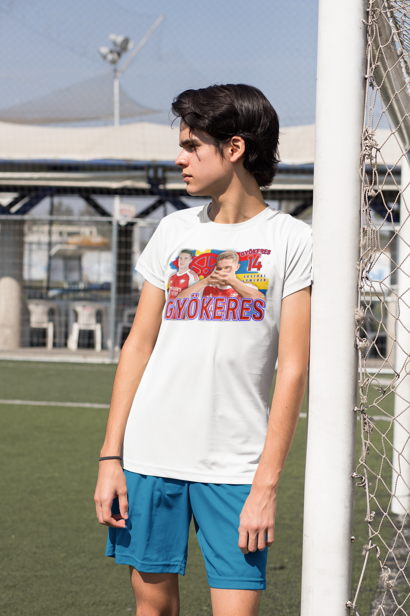 Person wearing a white arsenal t-shirt with gyokeres graphics and text, standing near a soccer goal.