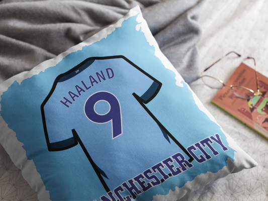 Pillow with Manchester City jersey design featuring 'Haaland' and number '9' on a bed.