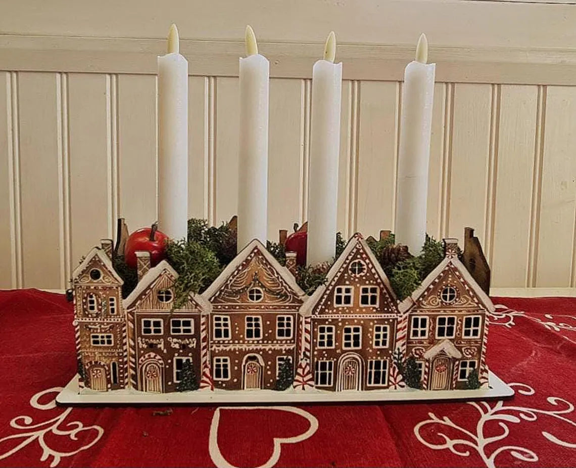 Decorative candle holder with gingerbread house design on a red tablecloth.