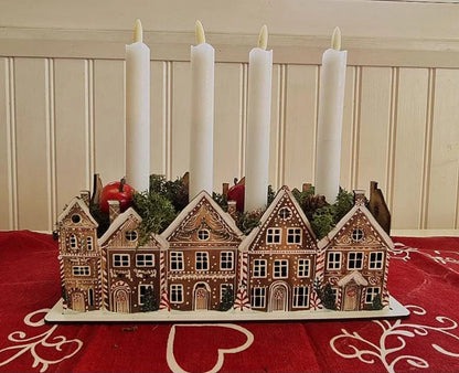 Decorative candle holder with gingerbread house design on a red tablecloth.