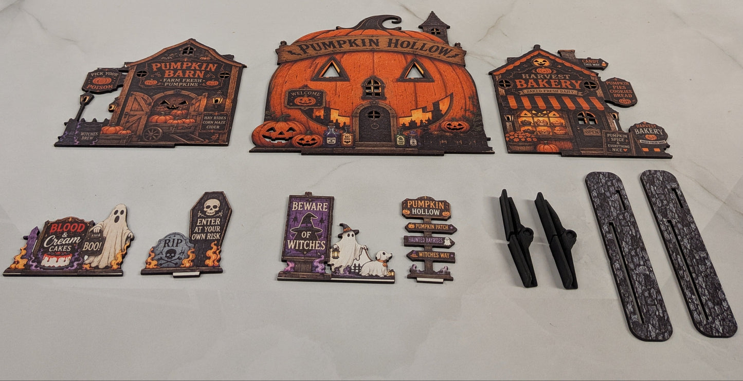 A set of Halloween-themed decorative signs and accessories arranged on a light marble surface. The set includes three large haunted-house style signs reading Pumpkin Patch, Pumpkin Hollow, and Candy Cane Shop, several smaller tombstone and sign pieces with spooky text, two black hanging clips, and two gray textured vertical panels.