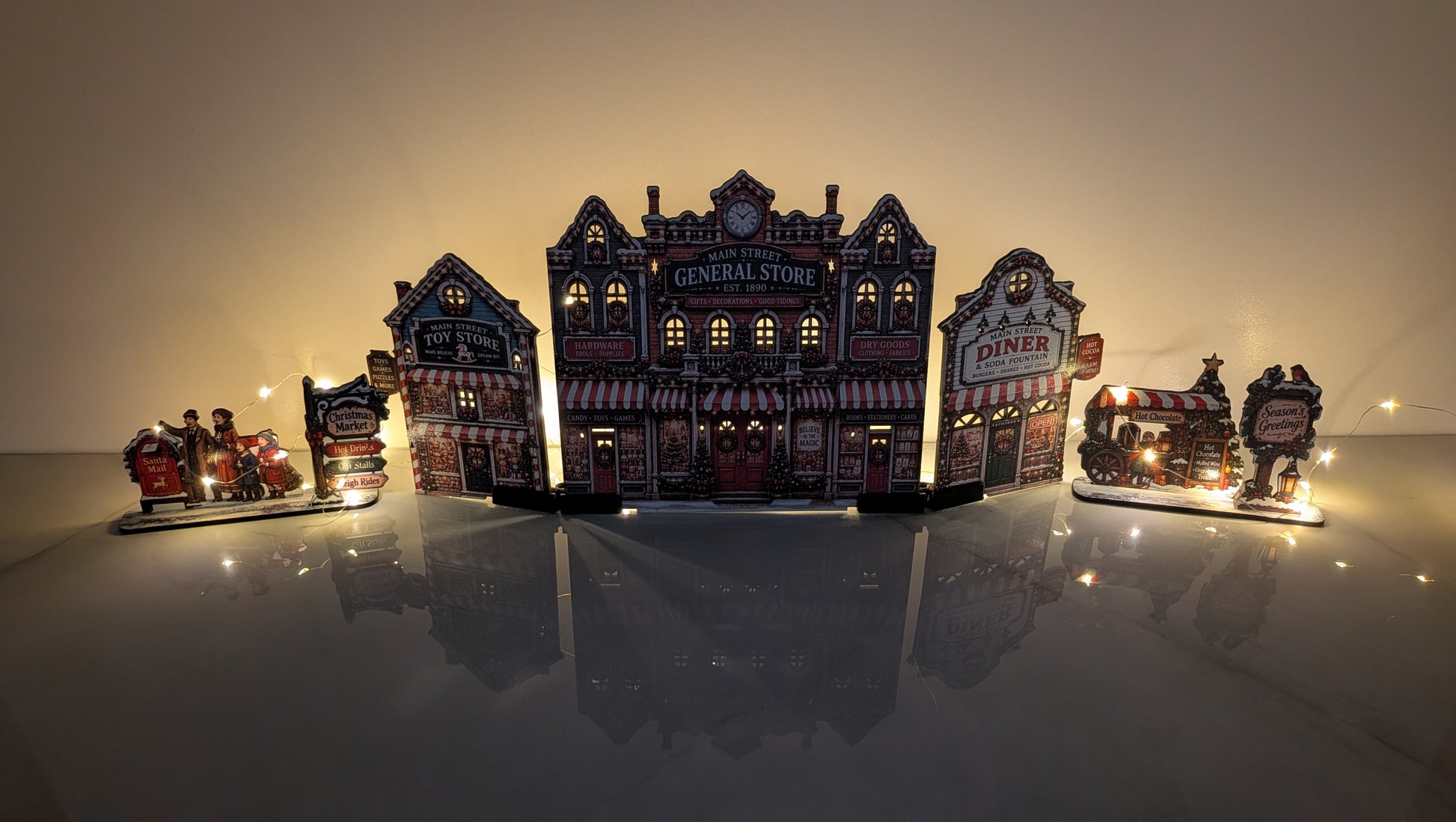 A miniature diorama set featuring a central vintage general store with glowing windows, flanked by a diner, a small train car, and decorative street signs, displayed on a reflective surface against a warm gradient background.